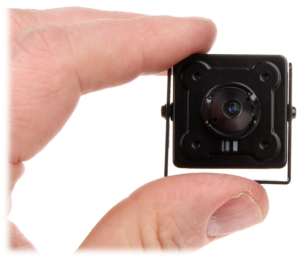 Mini cámara de seguridad tipo pinhole negra, sostenida entre los dedos, ideal para vigilancia