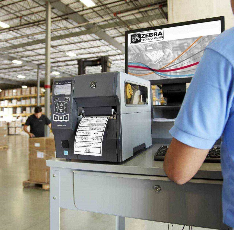 Impresora de etiquetas Zebra industrial en almacén, impresión de códigos de barras.